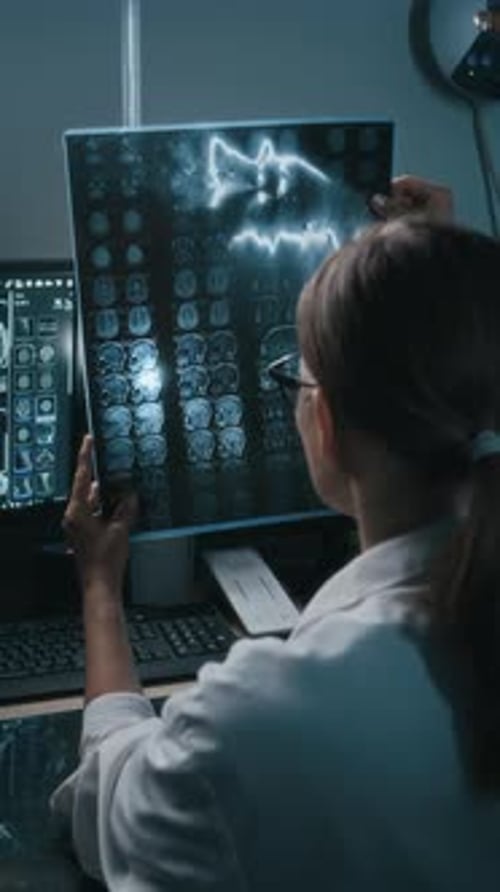 Female Doctor Examining Brain Scan in Dark Room