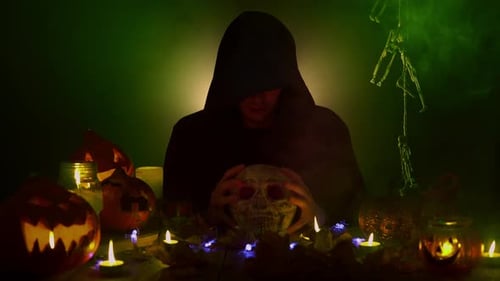 Man in Black Hood is Holding the Skull and Saying the Spell Aloud
