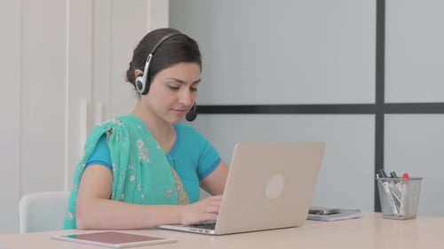 Young Indian Woman with Headset Working on Laptop in Call Center