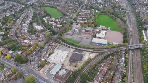 Drone footage capturing Underground train arrival at North Ealing Station with surrounding urban