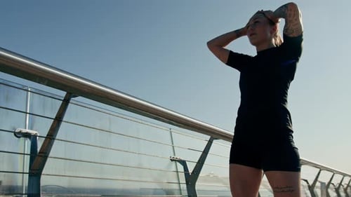 Fitness young sportswoman girl tired after doing sports training outdoors in the city on the bridge