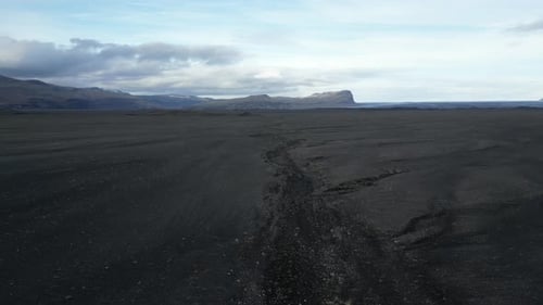 Black sands leading down to mountains in the South of Iceland, aerial.
