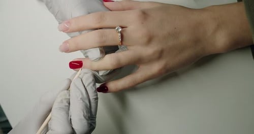 Woman Manicurist in Latex Gloves Covers Female Client Nails with Red Polish