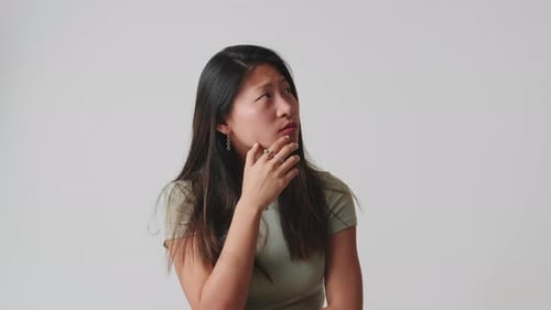 Young woman thinking and making decision isolated over white background in studio