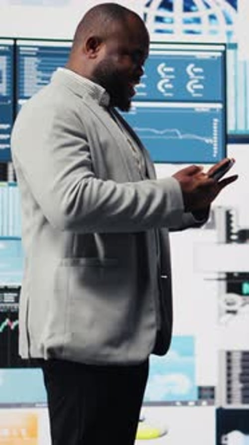 Well-dressed Man Uses Phone in Tech-filled Office