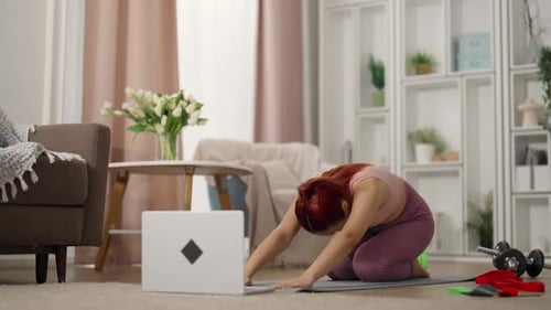 Mujer china entrenando sola en casa viendo un vídeo tutorial en la pantalla del ordenador portátil Entrenamiento deportivo en línea