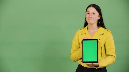 A Caucasian Woman Shows a Tablet with Green Screen to the Camera Green Screen Studio