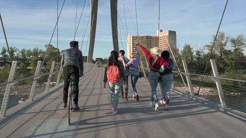 Group of friends walk across urban cable bridge