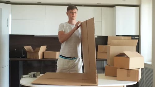 Man Assembling a Cardboard Box in Kitchen