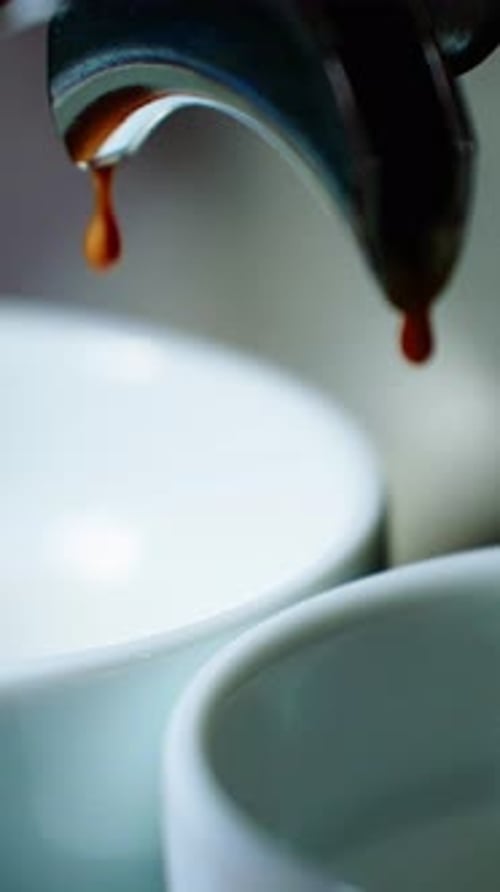 Coffee Drips From Espresso Machine Into White Cups at a Cozy Cafe