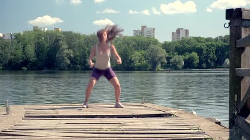 The Girl Has an Athletic Body Jump Squats Sports Activities on the Lake
