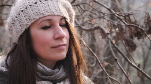 Beautiful Woman With Knitted Hat And Brown Hair In The Forest Looks At The Sun Then Smiles At The Ca