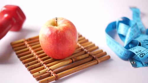 Apple, Dumbbell, and Measuring Tape on Tabletop