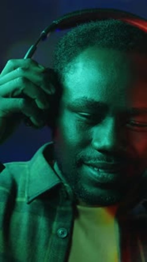 Vertical Portrait of African American Gamer in Headset in Neon Room