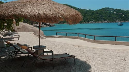 Enjoy the Beautiful Blue Sea From a Comfortable Beach Chair with Straw Umbrella