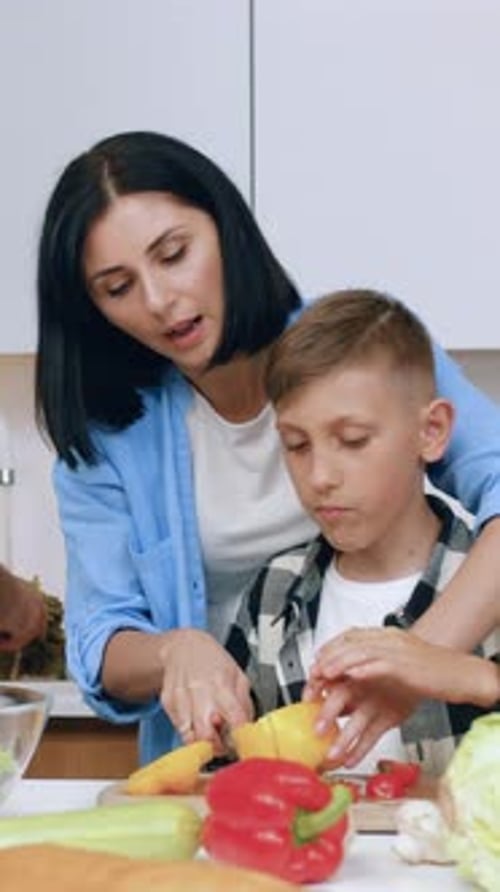 Woman and Child Cutting Vegetables in the Kitchen