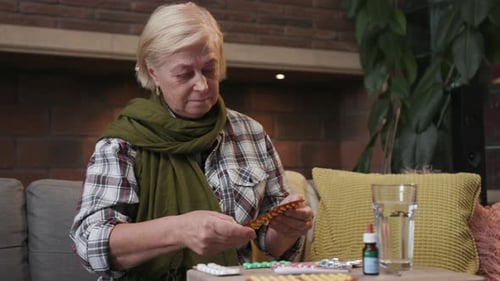 Senior Woman Taking Medication with Water Indoors