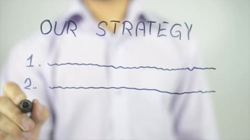 Man Writes Our Strategy on Clear Surface