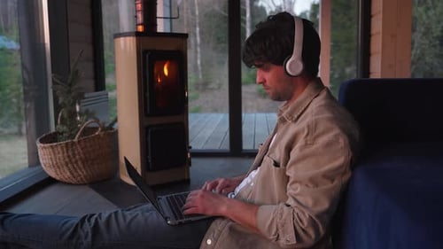 Man Works on Laptop by Fireplace at Home