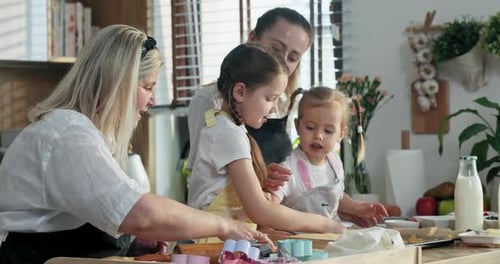 Glückliche Mutter mit Großmutter und Töchtern beim gemeinsamen Kochen in moderner Küche