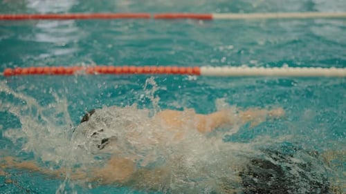 Athlete in Cap Swimming Freestyle in Competitive Pool