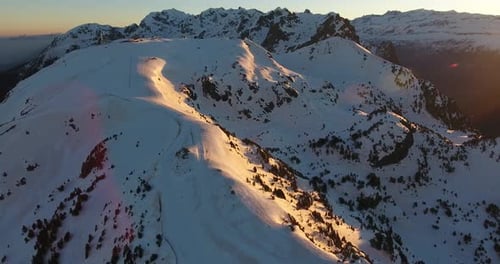 Stunning Sunset Aerial View Over Snowy Mountain Peaks and Slopes