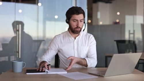 Businessman in Headset Having Video Call on Laptop in Modern Office