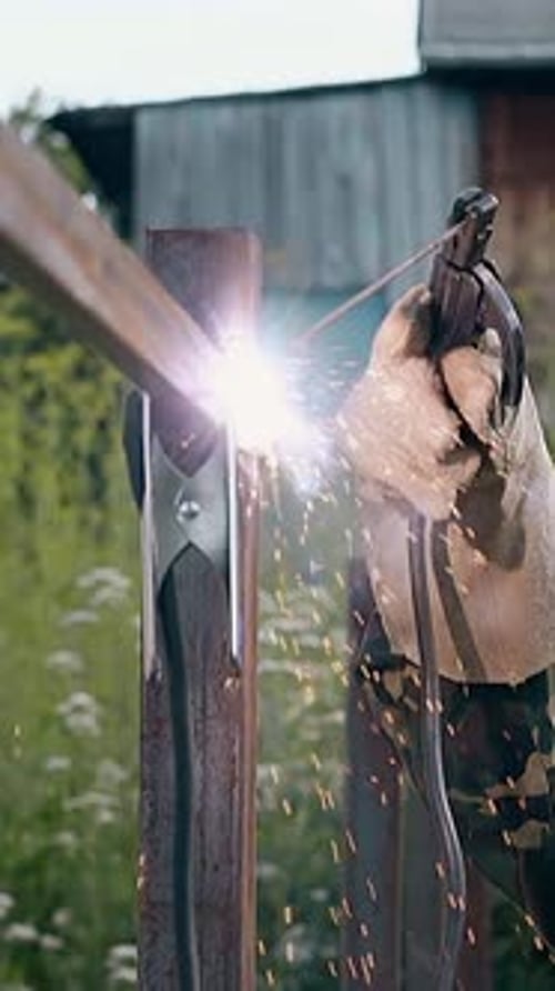 Slow Motion Side View Welder Connects Upper Rail to Fence