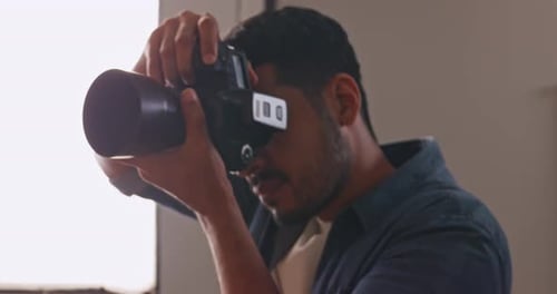 Professional male photographer working in studio. Photographer shooting model with flashlight.