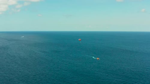 Tourists on a Parachute Over the Sea