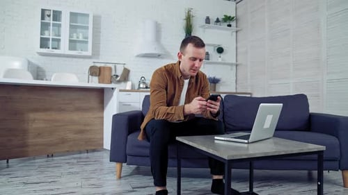 Man Relaxing on Sofa Using Smartphone