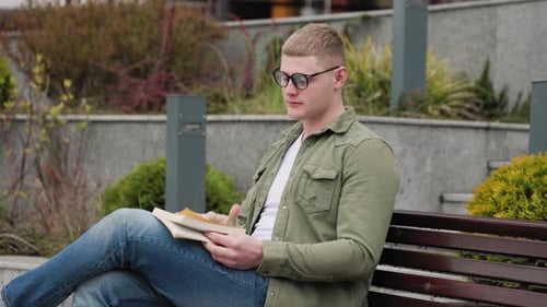 Junger Mann vertieft in das Lesen im Freien