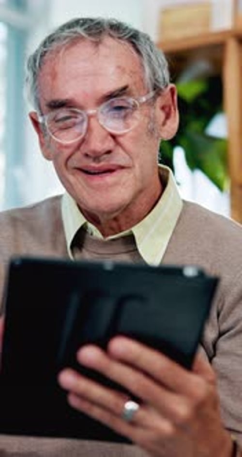 Gray-Haired Man Smiling and Using a Tablet