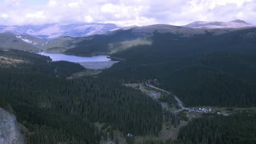 High drone view of mountains with a trail going to a lake 4K