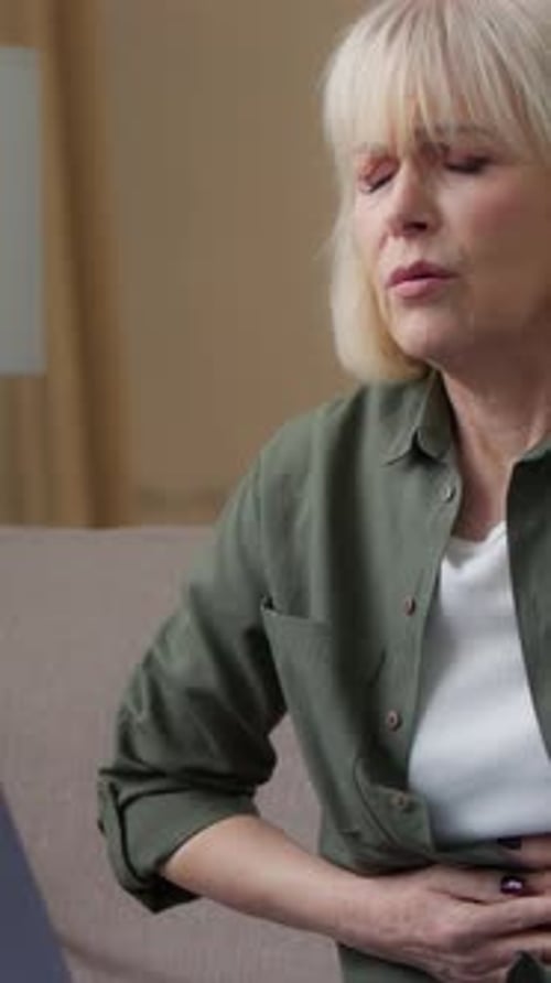 Blonde Woman Experiencing Stomach Pain on a Couch