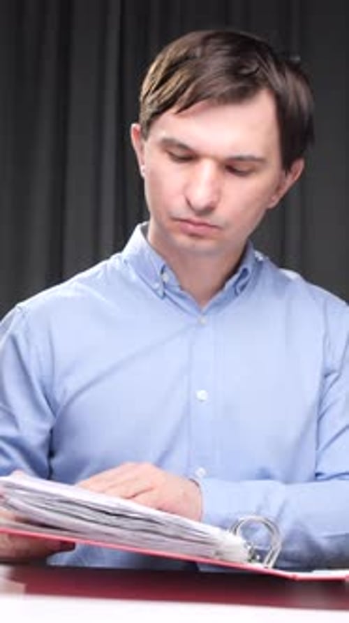 Vertical Video Office Worker Reviewing Documents in Red Folder at Desk