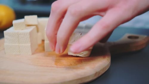 Hands Cutting Tofu with Knife on Cutting Board