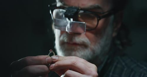 Slow motion of experienced goldsmith controlling a quality of just finished handmade jewelry ring
