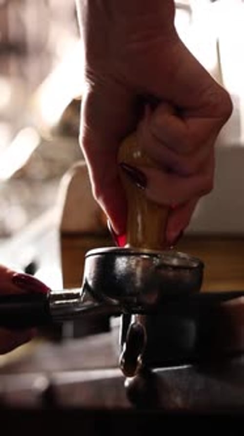 Hand Tampers Coffee Grinds in a Metal Portafilter