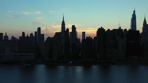 Dramático subida e inclinación aéreas hacia el legendario horizonte del Midtown Manhattan al anochecer