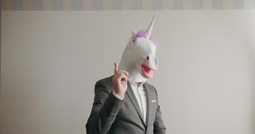 Hübscher glücklicher Geschäftsmann mit Einhornmaske