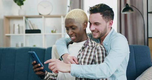 Happy Couple Looking at Smartphone Together on Couch