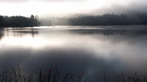 Time lapse of morning fog rolling over the lake. Rising sun with reflection sun and cloud on water s