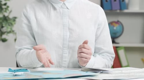 Person Gesturing While Planning Travel at Desk