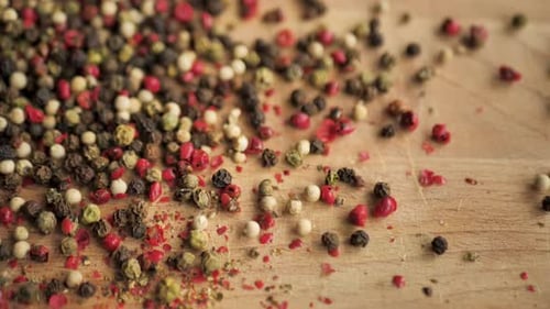 Mixed Peppercorns Pouring onto a Wooden Surface