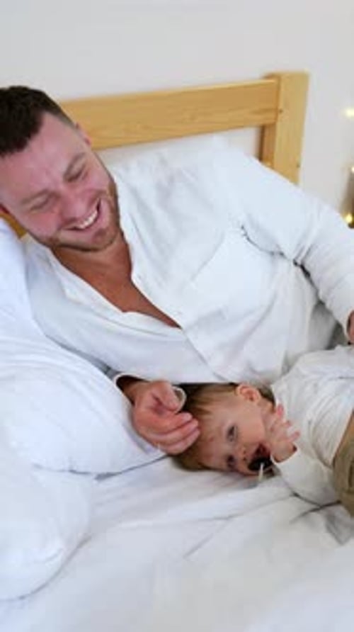 Loving Father Playing with Baby in Bed