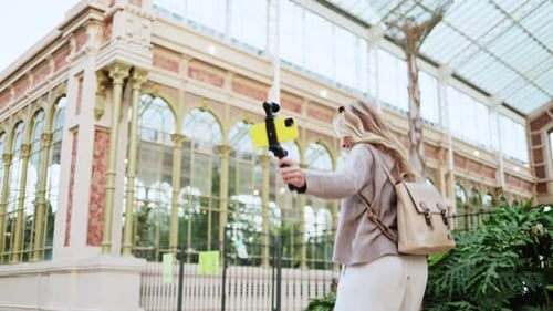 Woman Recording Video with Smartphone Near Glass Building