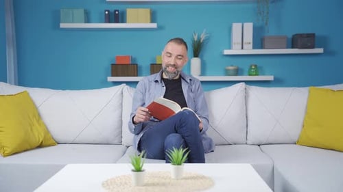 Bearded Man Reading a Book on the Couch