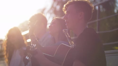Young Friends Singing Songs with a Guitar in the Park