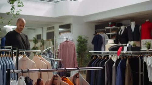 Asian Woman Store Employee Arranging New Designer Clothes on Hangers
